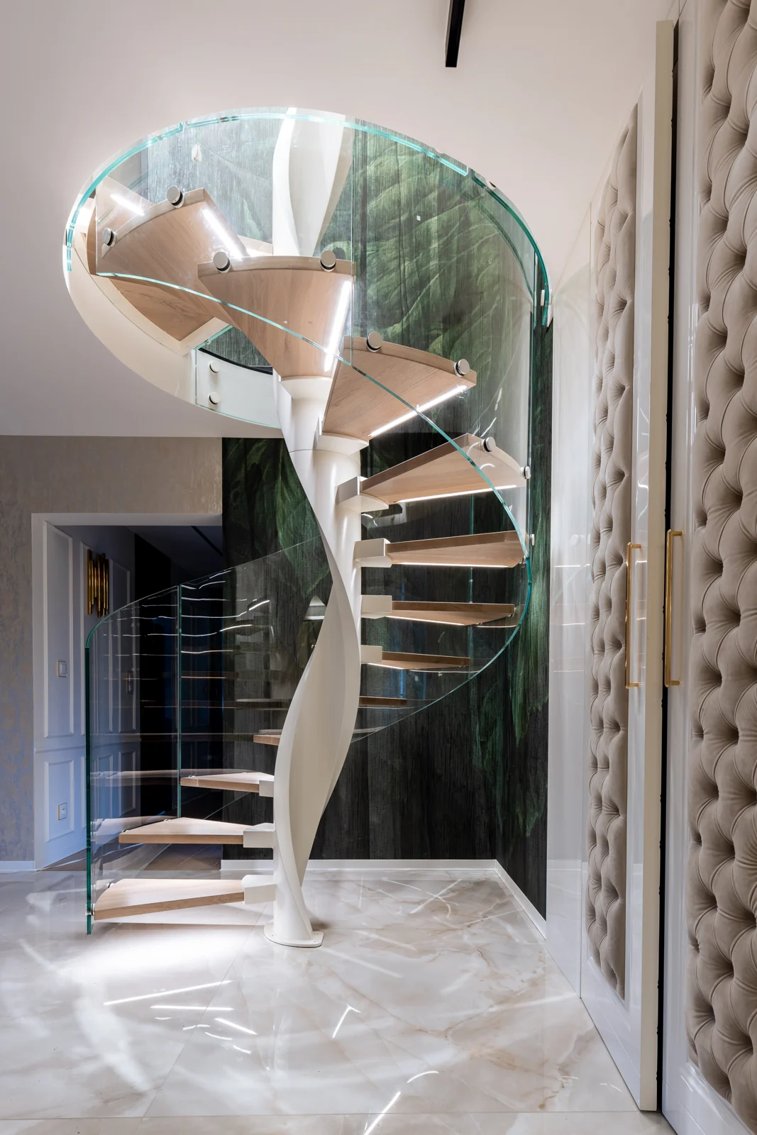Pełny widok spiralnych schodów z giętą szklaną balustradą