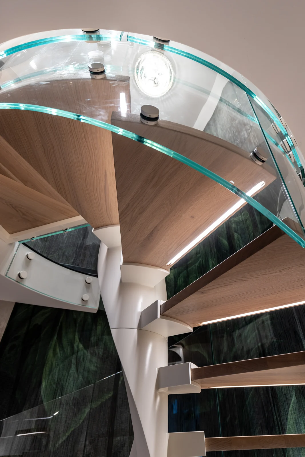 Detal drewnianych stopni i giętej balustrady szklanej